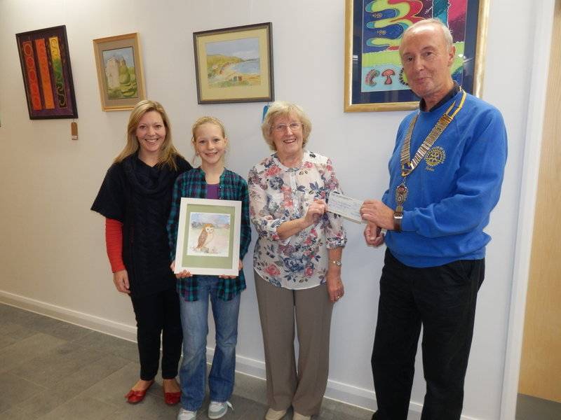 Local artist, Anne Jackson presents a cheque for £415 to Dunbar Rotary Club President Robin Hamilton at Dunbar’s new Community Centre. L to R.  Successful bidders Nicola and Emma Lonie, Anne Jackson and Robin Hamilton.