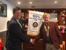 Assistant Governor Duncan Collinson presenting President Calum Thomson with a banner from the Rotary Foundation marking the achievement of having 100% Paul Harris Fellows in the Club
