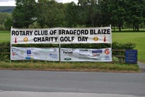 A photograph of Ilkley Golf Course with the sponsors names on one banner and the charities supported on the other