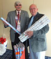 President David Knight hands over some of the 500 rolls of wrapping paper to PDG Terry Watts who is a trustee of the charity Toys on the Table, along with his wife, Margaret.
