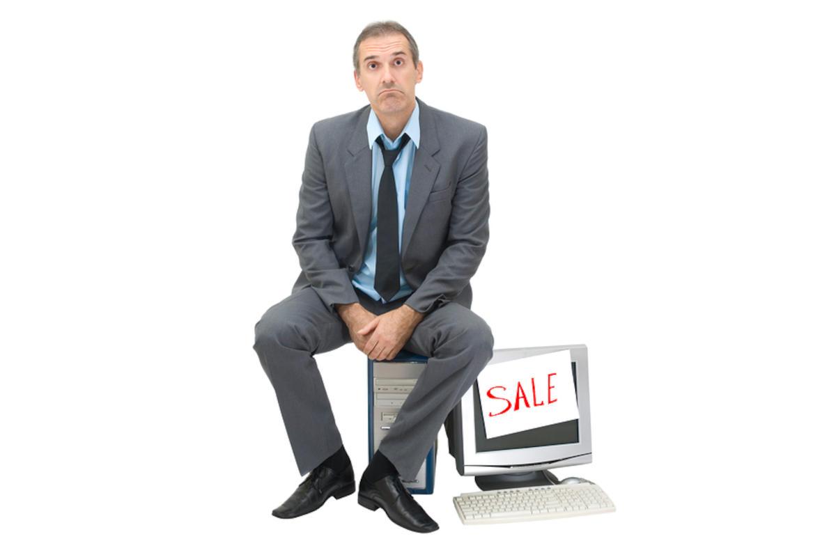 Disconsolate man sitting on top of a computer tower.