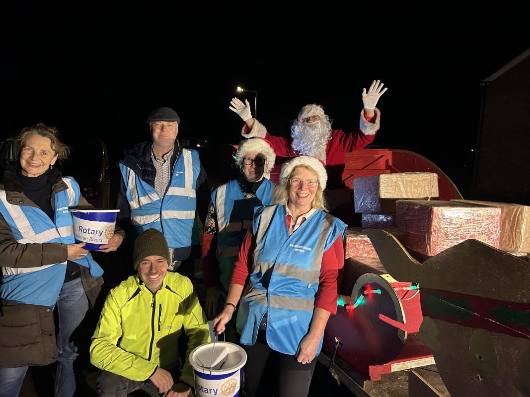 Santa and his helpers wearing santa hats and carrying collecting buckets