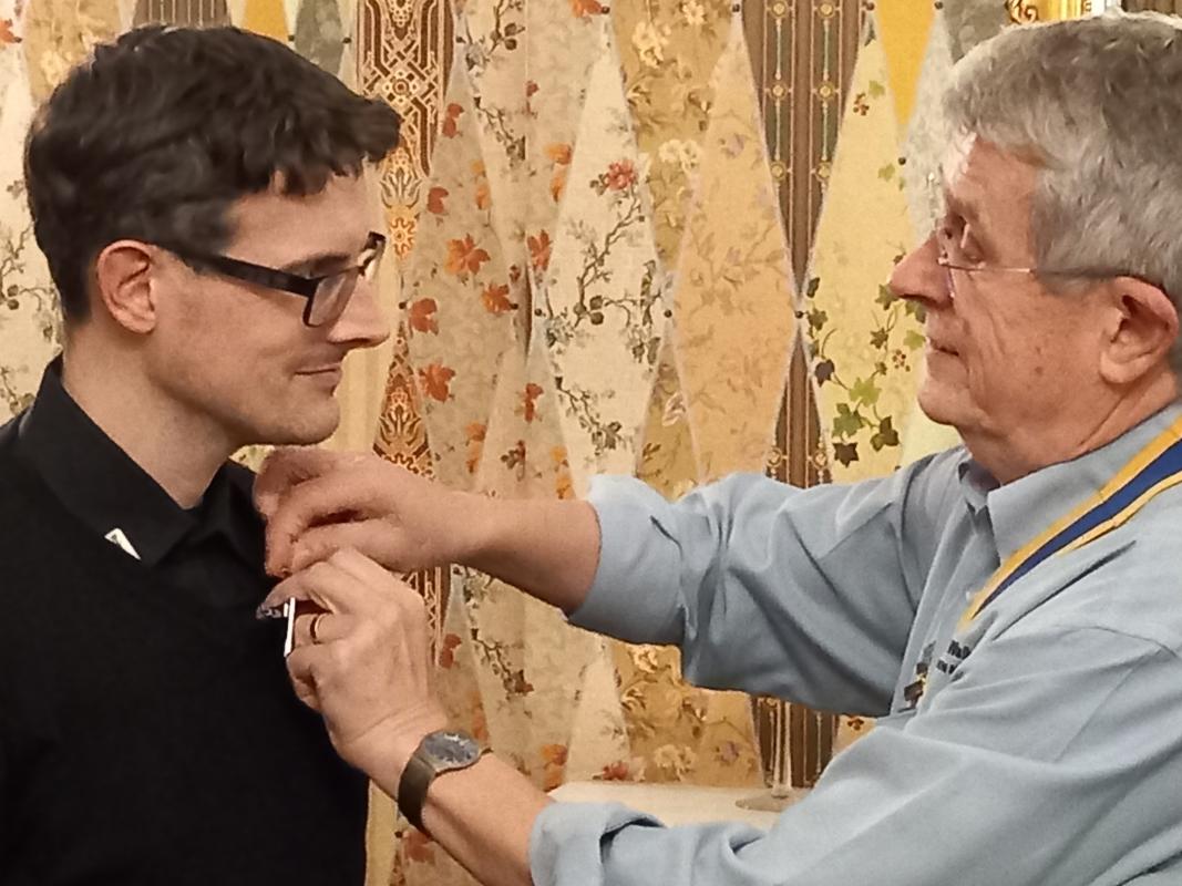 President Andrew Barwood presents a  Rotary members badge to his son Michael Barwood.