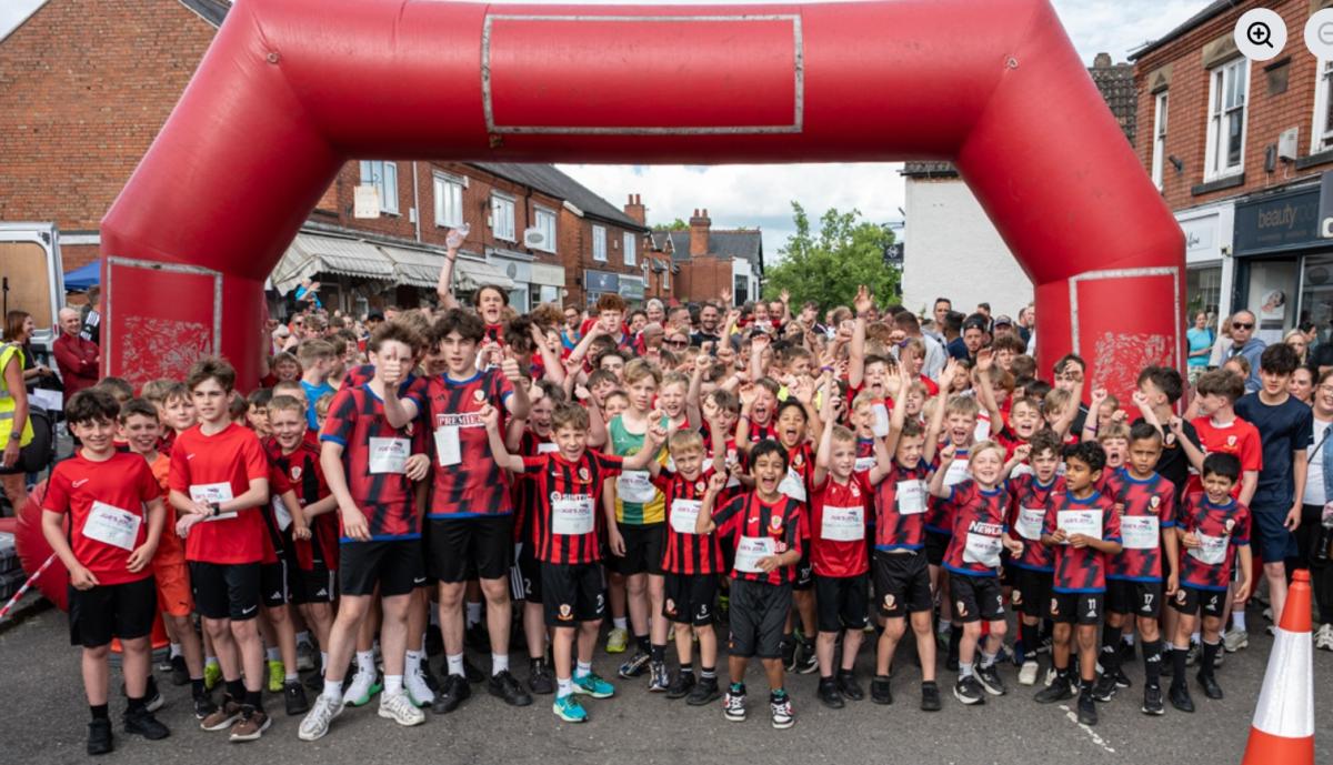 Hundreds of young runners line up under a red inflatable start line 