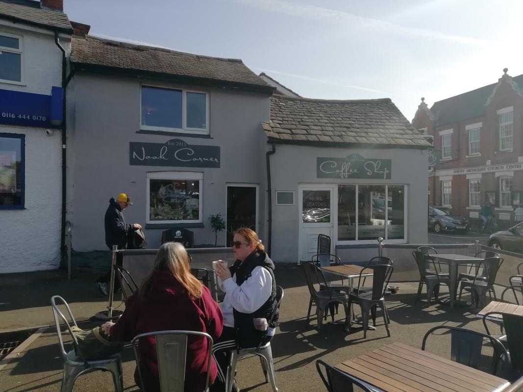 External view of The Nook Corner Coffee Shop, Anstey, with customers sitting in the sunshine