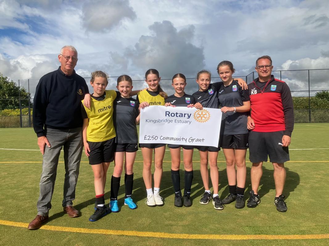 Peter Bromfield (Kingsbridge Estuary Rotary Club) presenting the June 2024 Community grant to Kevin Broom KM United Youth FC and some of the Under14 girls team.
