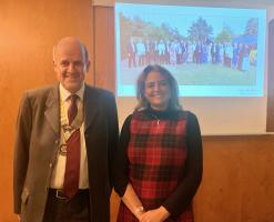 The photo below shows Lucy with Rotary Club President Mark Loader against a background picture of Club’s fellowship event at Fredrick’s. 