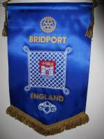 The central Shield is the Borough Coat of Arms which was granted to Bridport in 1623. In the open port are three spinning cogs or hooks.