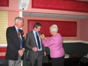 Rotarian Frances Smith pins on Charlie Homer's Rotary pin after his induction