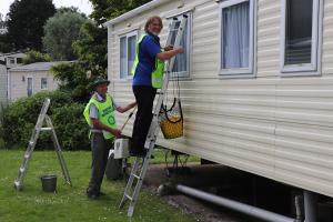 Geoff Lowles and Mike Roper cleaning the exterior panelling working their way from the rear to the front of the caravan
