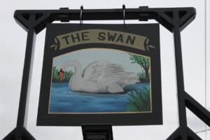 A picture of the pub sign featuring a white swan swimming in water