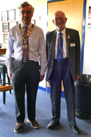 Two men standing side by side, one wearing a chain of office