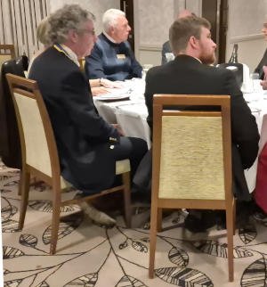 Two men sitting at a dining table, one wearing a President's chain of office and the other sporting a beard