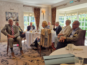 Photograph of people sitting around a dining table and looking to the viewer's left